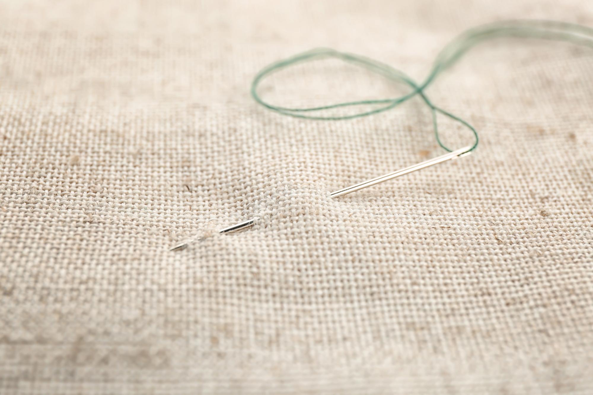Close-up of hand embroidery thread and needle on linen